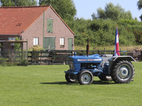 902465 Afbeelding van een tractor met eraan gehangen een omgekeerde Nederlandse vlag in een weiland bij boerderij ...